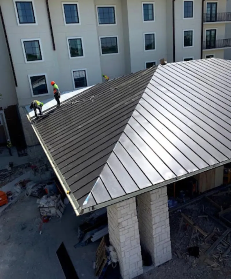 Crew installing standing seam metal roof panels on a commercial project in Azusa